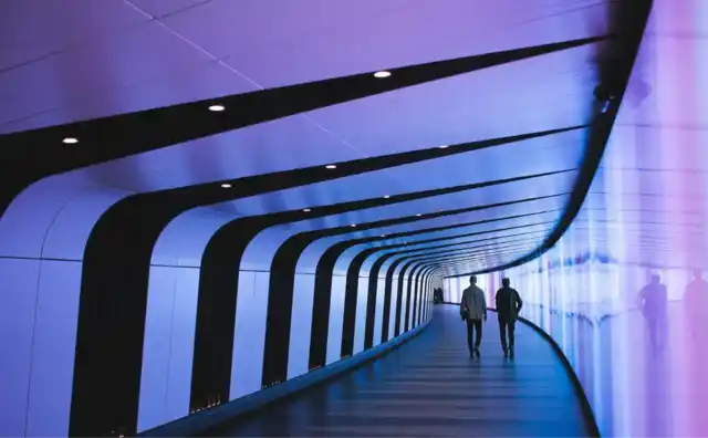People moving through a luminous curved passageway