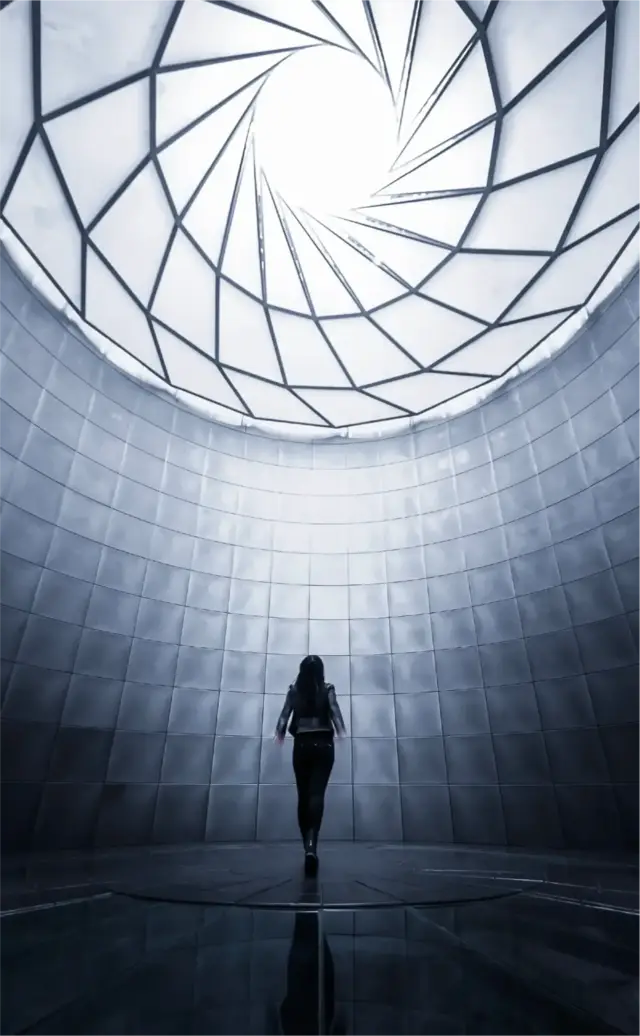 A lone figure in silhouette walking into a domed skylight
