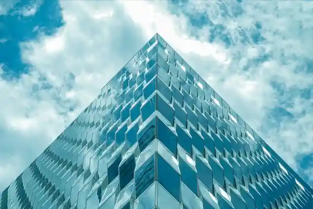 Blue glass tower rising into a cloud-filled sky
