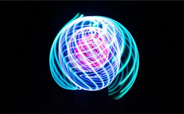 Circular blue and magenta light trails drawn against a black field